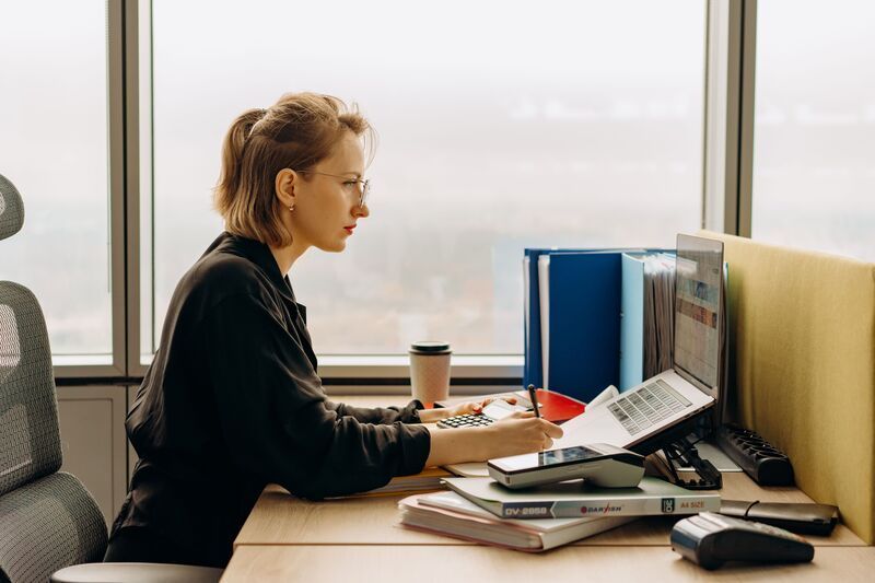 Employée concentrée travaillant sur ordinateur au bureau.